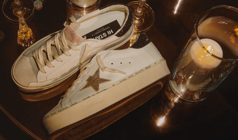 white-hi-star-sneaker-with-gold-star-on-table-with-candle