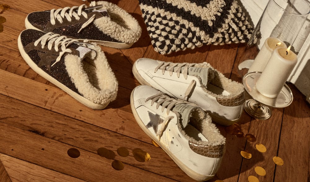 two-pair-of-sabot-sneakers-on-wooden-floor-with-white-candles