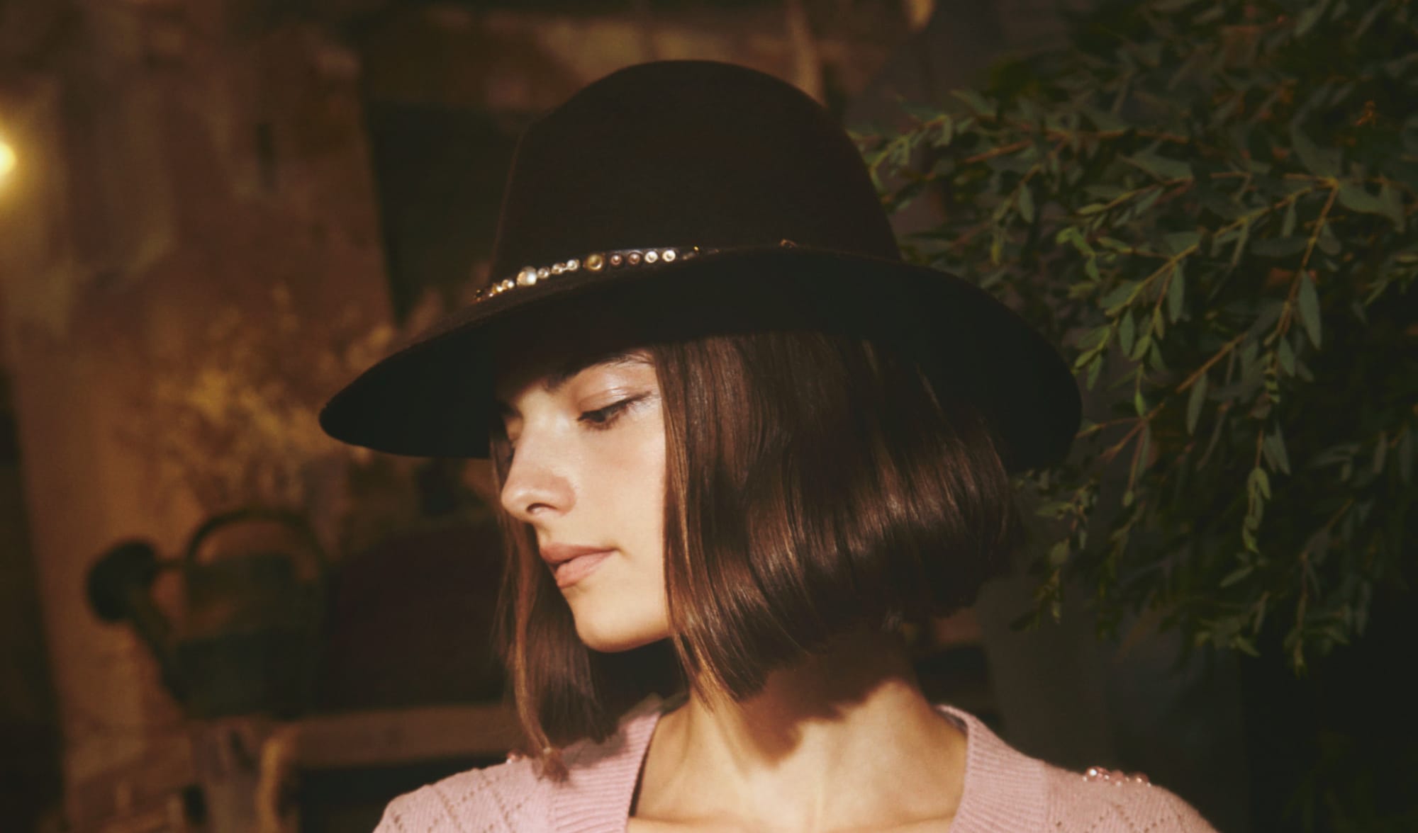 woman-with-brown-hair-and-brown-hat-with-metal-details