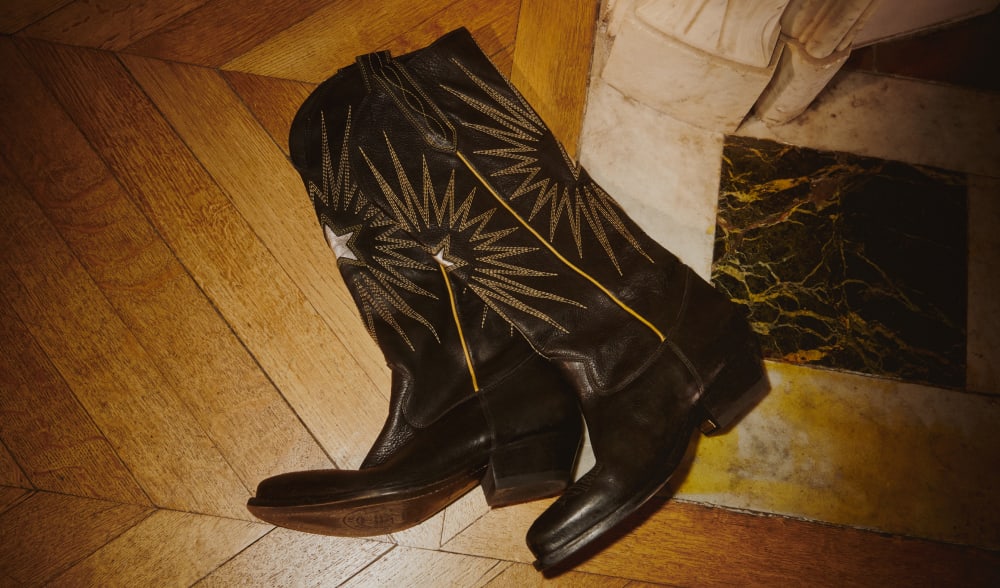 women-black-leather-boots-with-white-decorative-details-on-wooden-floor