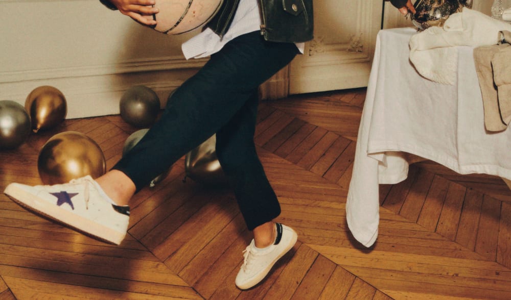legs-of-a-kid-wearing-black-trousers-jacket-running-on-wooden-parquet-floor-with-basket-ball-next-to-table-during-party-