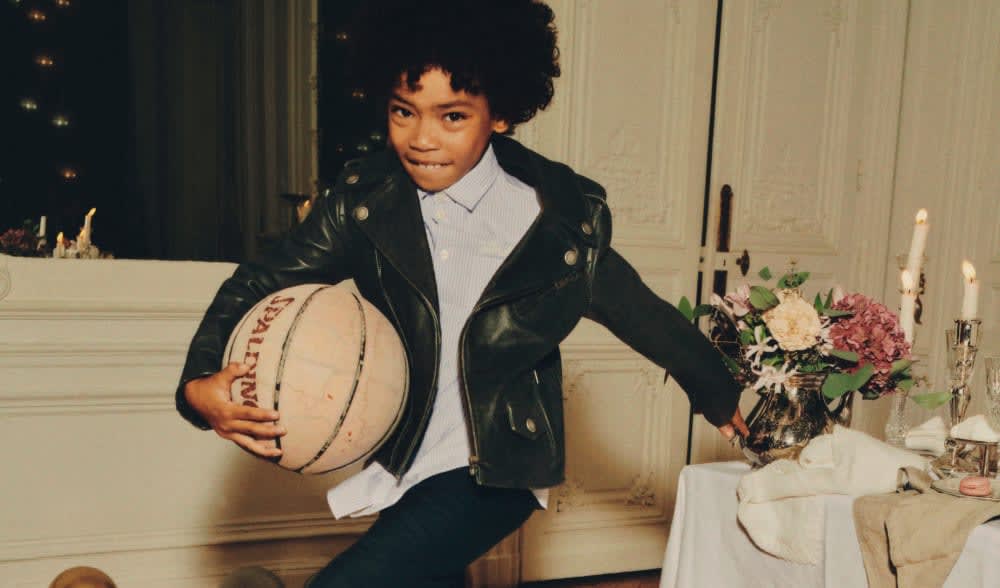 kid-wearing-black-leather-jacket-running-with-basket-ball-next-to-table-during-party