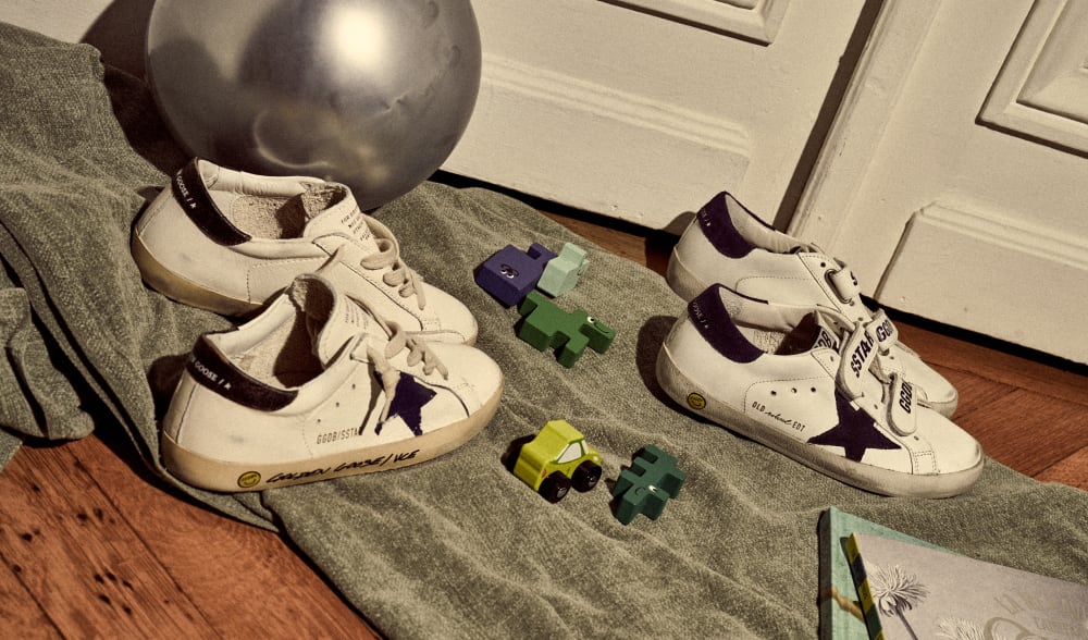 white-super-star-and-old-school-sneakers-with-black-star-on-grey-blanket-on-wooden-floor-with-car-toys