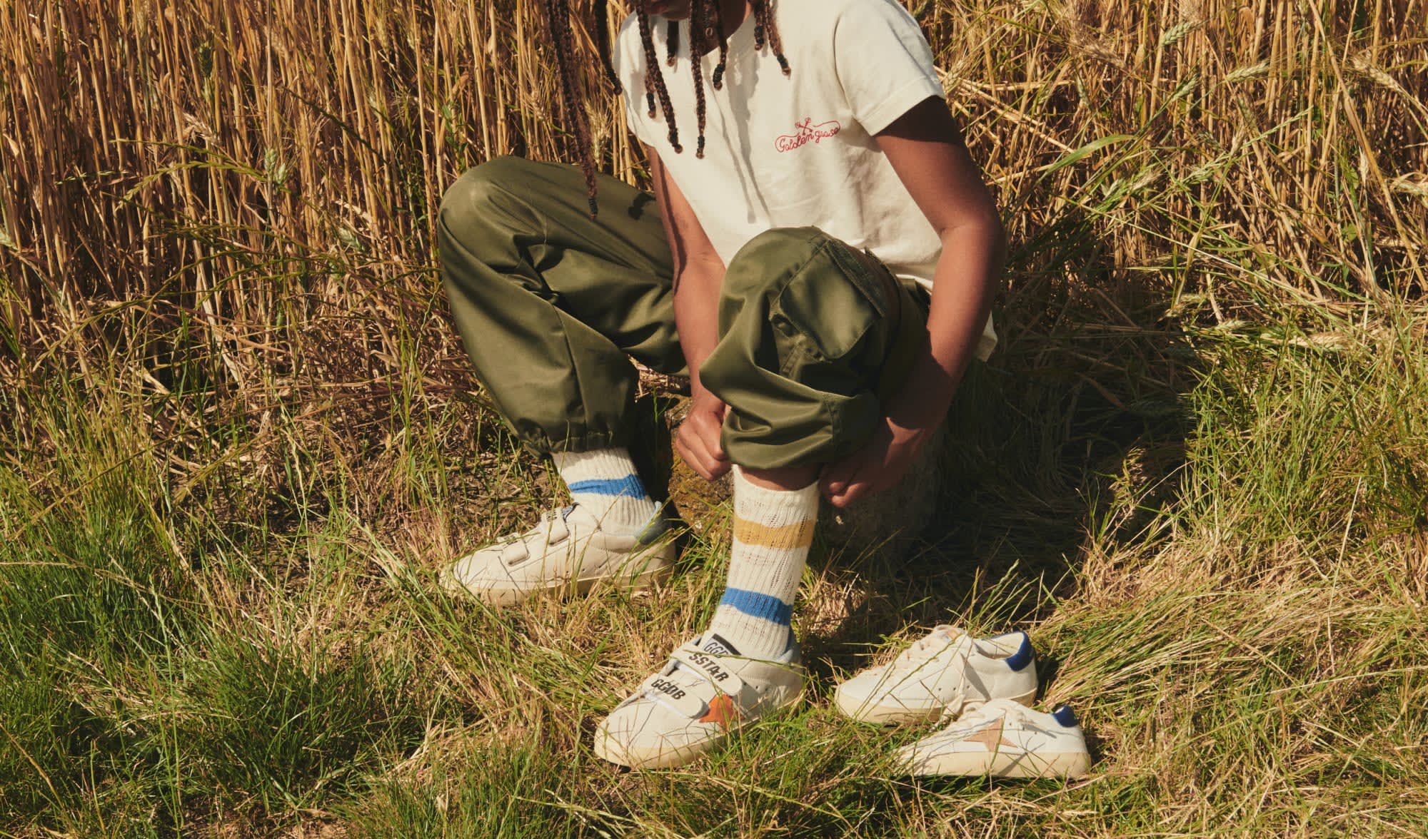 white-super-star-and-old-school-sneakers-with-black-star-on-grey-blanket-on-wooden-floor-with-car-toys