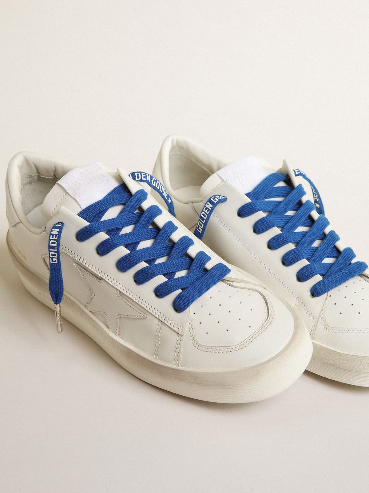 Tenis blancos con degradado del logotipo en azul y detalle del